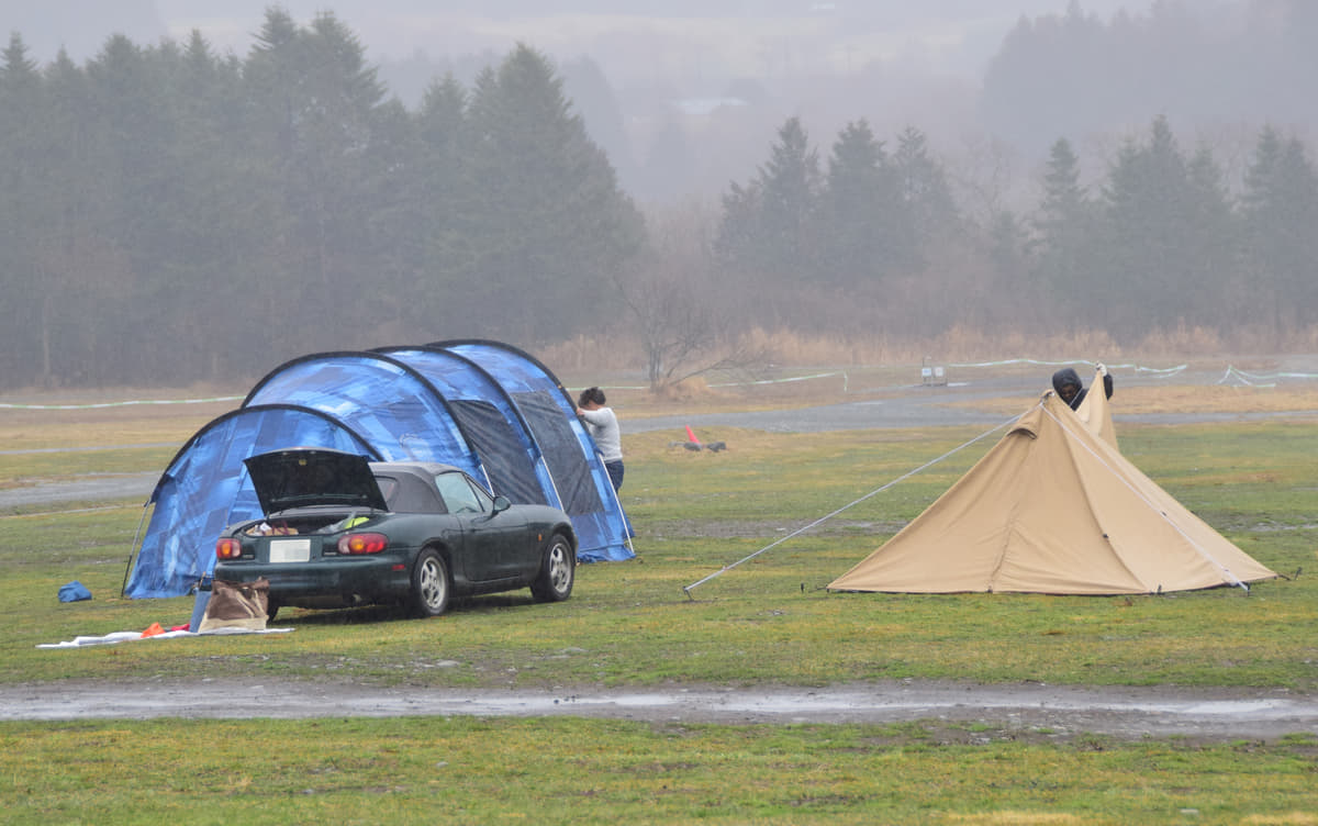 雨の中、テントをしまうキャンパー
