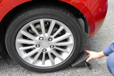 交換するタイヤの対角線上の車輪に輪留めをしてクルマが動かないことをしっかり確認する