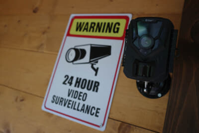 警告板で監視カメラの存在をアピール。カメラはホームセンターでまとめて購入した。センサーの感度なども細かく設定できる