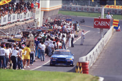 R32参戦初年度となる'90年の筑波サーキット。レース・ド・ニッポンでカルソニック スカイラインは勝利を収めている。星野一義と共にステアリングを握ったのは鈴木利男。当時の観客の多さにも驚かされる