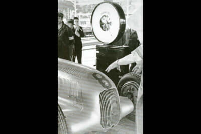 アルフレッド・ノイバウアー監督の指示の元、メルセデス・ベンツのエンジニアたちはドイツのナショナルカラーであるホワイトのペイントを徹夜で全てはがし、750kgで出場許可を得たことで、アルミ地肌の「シルバーアロー」のW25が誕生。写真は750kgの重量計測のシーン